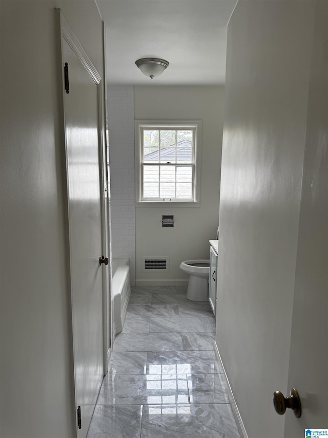 bathroom with a bathtub, vanity, and toilet