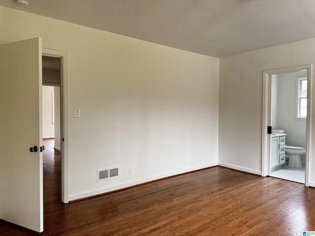 unfurnished bedroom featuring dark hardwood / wood-style flooring and ensuite bath