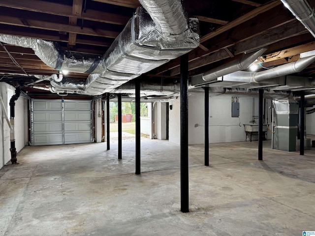 garage featuring electric panel, heating unit, and sink