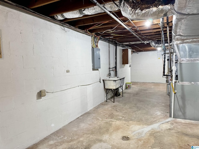 basement featuring electric panel, heating unit, and sink