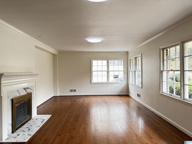 unfurnished living room featuring crown molding, a wealth of natural light, a fireplace, and dark wood-type flooring