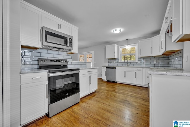 kitchen featuring sink, stainless steel appliances, tasteful backsplash, light hardwood / wood-style floors, and white cabinets