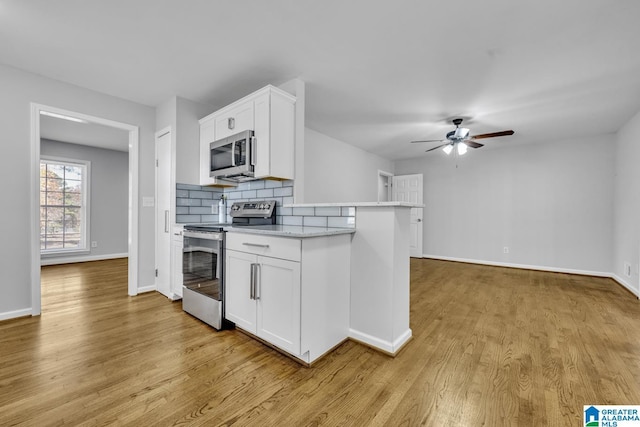 kitchen with appliances with stainless steel finishes, light hardwood / wood-style flooring, white cabinetry, and ceiling fan