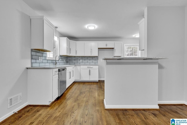 kitchen with dishwasher, pendant lighting, decorative backsplash, white cabinets, and light wood-type flooring