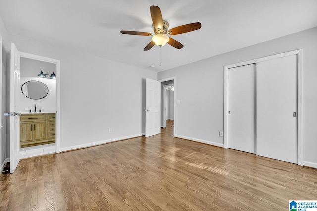 unfurnished bedroom featuring ceiling fan, sink, connected bathroom, and light hardwood / wood-style flooring