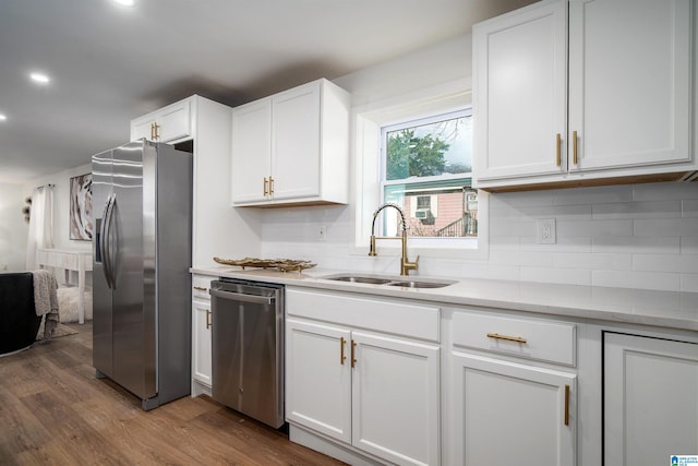 kitchen with appliances with stainless steel finishes, dark hardwood / wood-style flooring, backsplash, sink, and white cabinetry