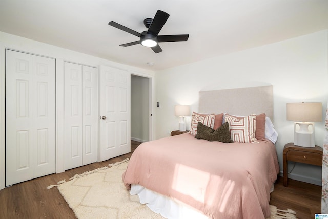 bedroom featuring ceiling fan, dark wood-type flooring, and multiple closets