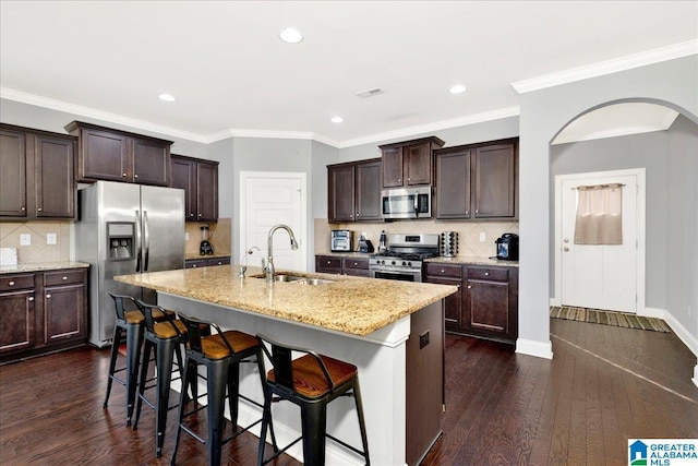 kitchen featuring appliances with stainless steel finishes, sink, dark wood-type flooring, and an island with sink