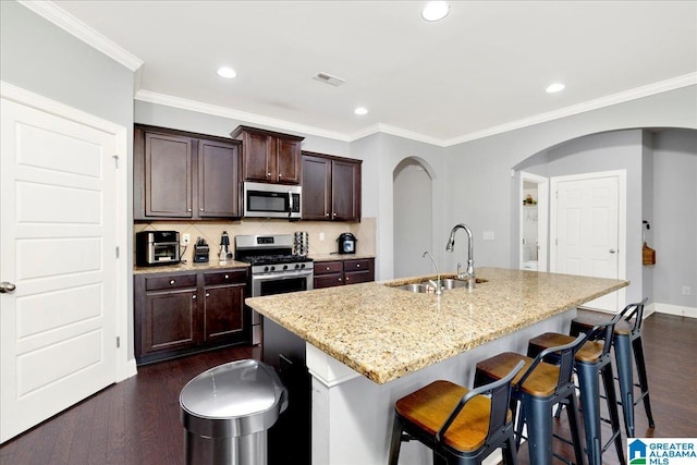 kitchen featuring light stone countertops, sink, dark wood-type flooring, stainless steel appliances, and a kitchen island with sink