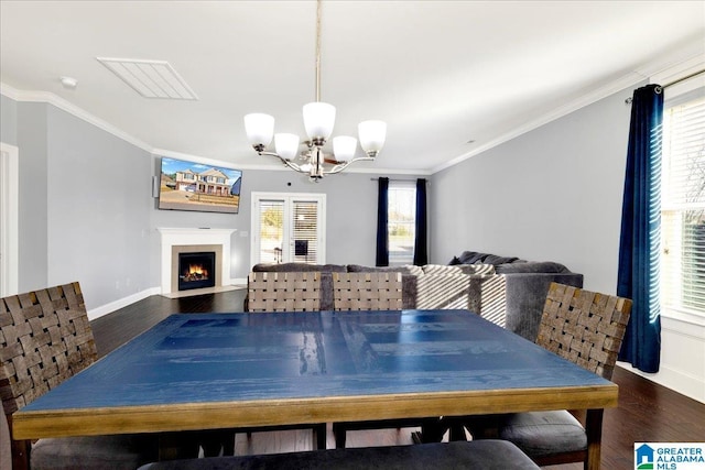 dining room with dark wood-type flooring, a healthy amount of sunlight, and ornamental molding