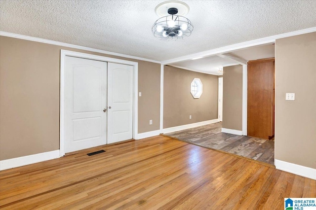 interior space with ornamental molding, a textured ceiling, and hardwood / wood-style flooring