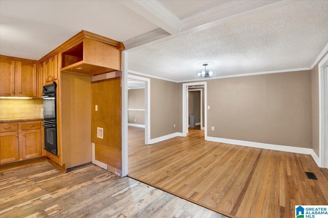 kitchen with hardwood / wood-style floors, crown molding, backsplash, and double oven