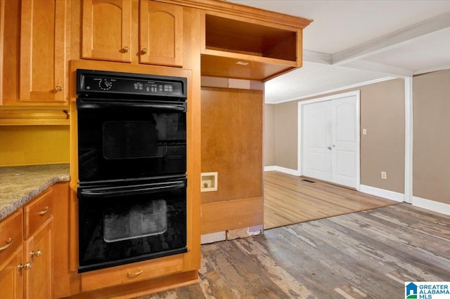 kitchen with hardwood / wood-style flooring, black double oven, and beamed ceiling