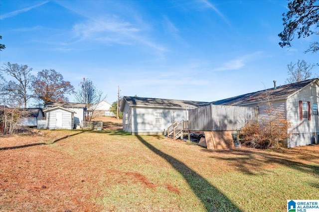 rear view of house with a lawn and a storage unit