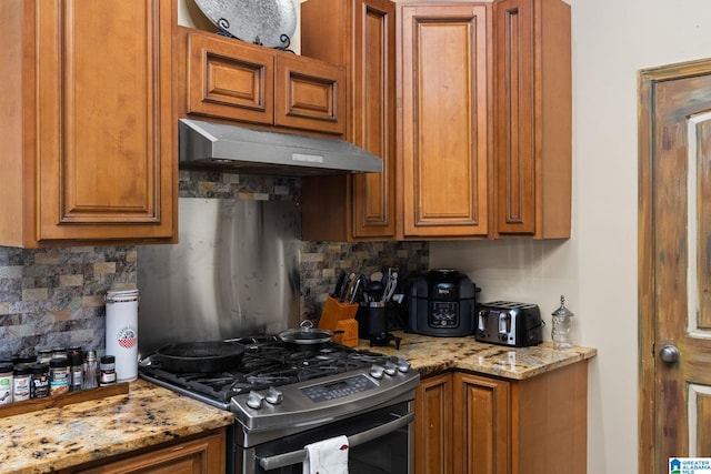 kitchen featuring tasteful backsplash, light stone counters, and stainless steel gas stove