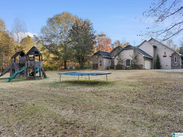 view of yard with a playground, a garage, and a trampoline