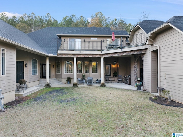 back of property featuring a balcony, a patio area, and a lawn