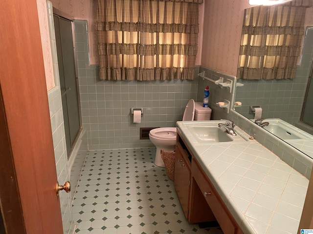 full bathroom featuring shower / bath combination with glass door, vanity, tile walls, and toilet