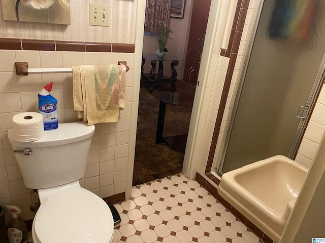 bathroom featuring a shower with door, toilet, tile walls, and sink