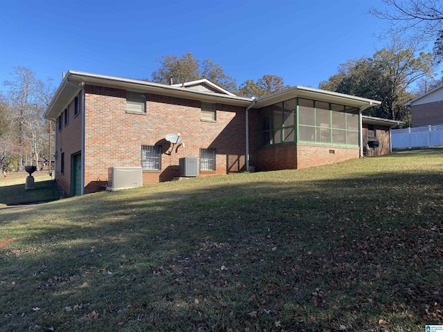 view of side of property featuring a sunroom, a garage, cooling unit, and a lawn