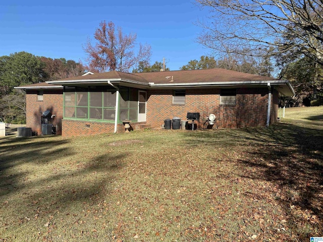 rear view of property featuring a lawn, a sunroom, and central AC