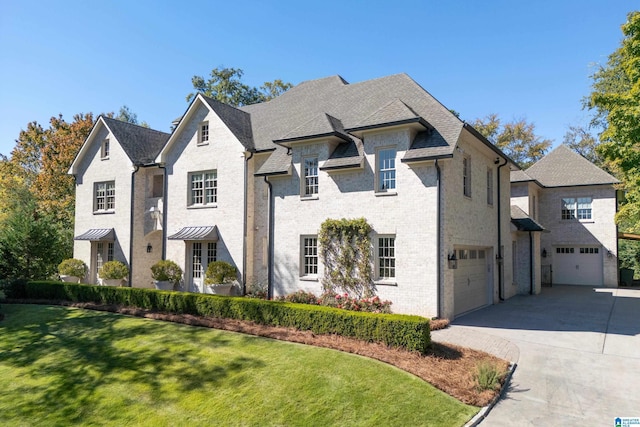 french country style house featuring a garage and a front lawn