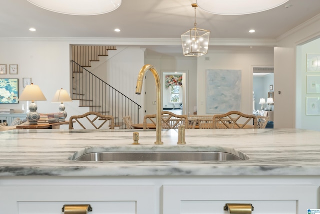 room details featuring white cabinets, ornamental molding, and sink