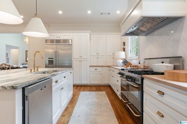 kitchen featuring sink, premium range hood, crown molding, white cabinets, and high end appliances