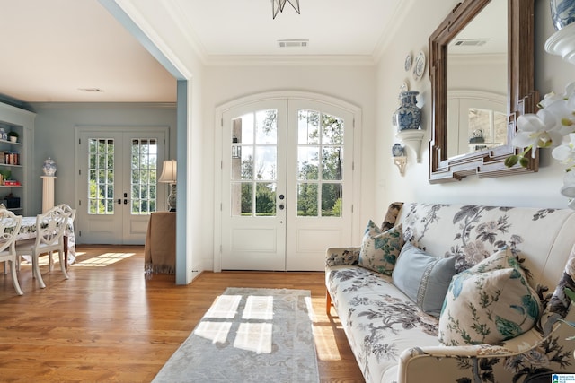 doorway to outside featuring a healthy amount of sunlight, crown molding, light hardwood / wood-style flooring, and french doors