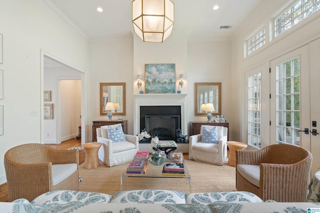 living room featuring french doors, a towering ceiling, light hardwood / wood-style floors, and ornamental molding