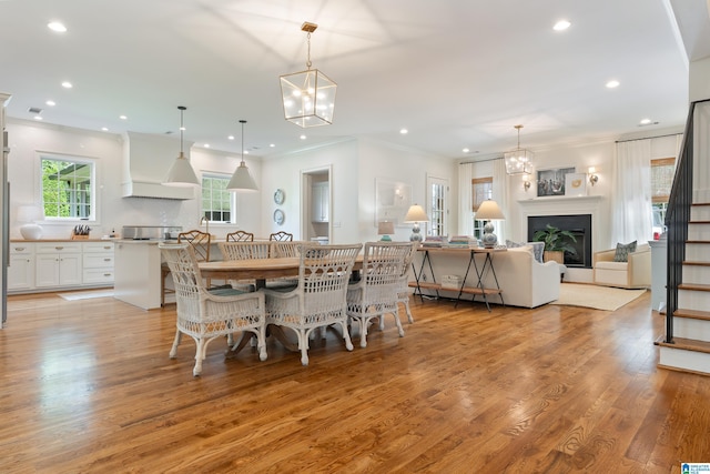 dining area with light hardwood / wood-style floors, an inviting chandelier, and ornamental molding