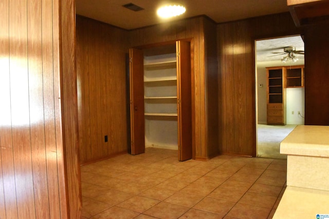 corridor featuring light tile patterned flooring, visible vents, and wood walls