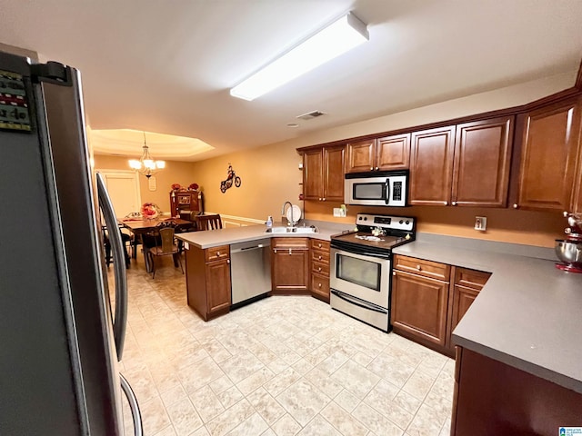 kitchen featuring kitchen peninsula, stainless steel appliances, sink, an inviting chandelier, and hanging light fixtures