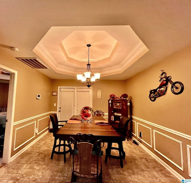 dining space with ornamental molding, a tray ceiling, and a notable chandelier