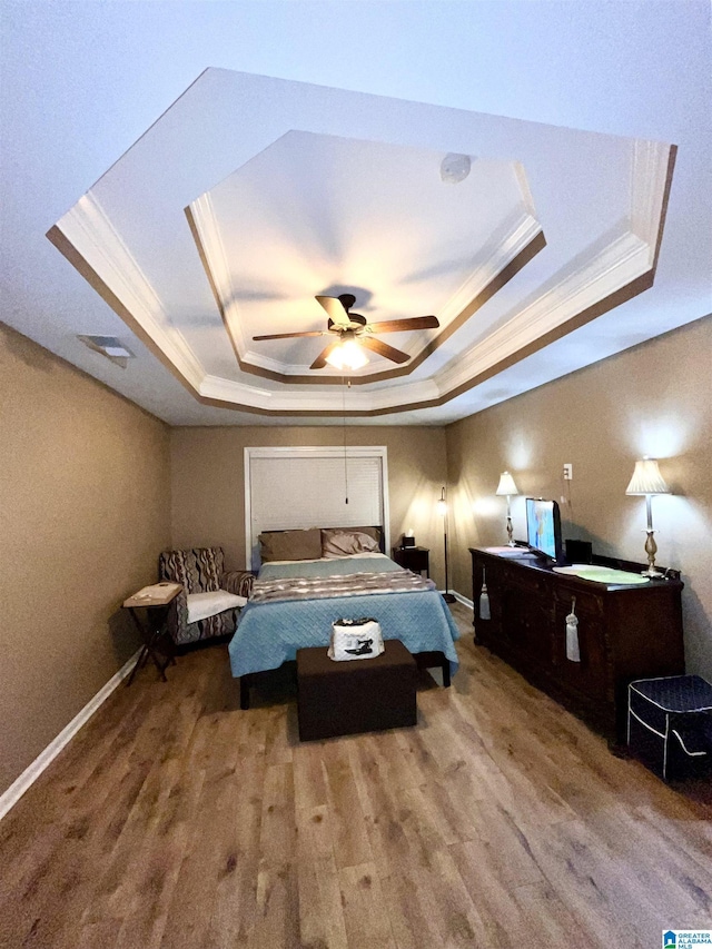 bedroom with a tray ceiling, ceiling fan, hardwood / wood-style flooring, and ornamental molding