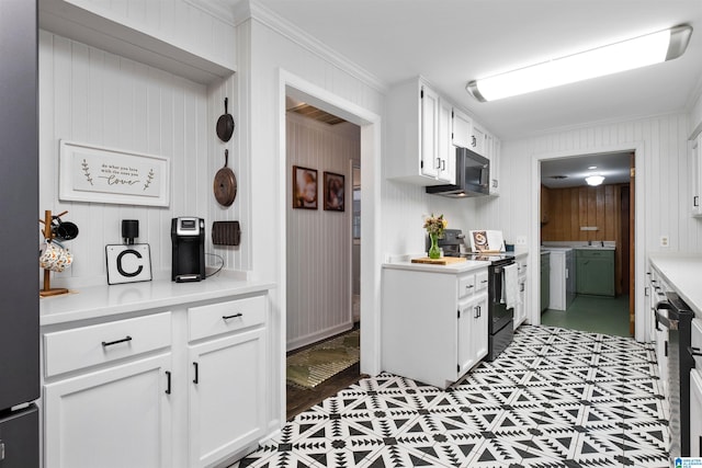 kitchen featuring black appliances, wood walls, white cabinets, and ornamental molding