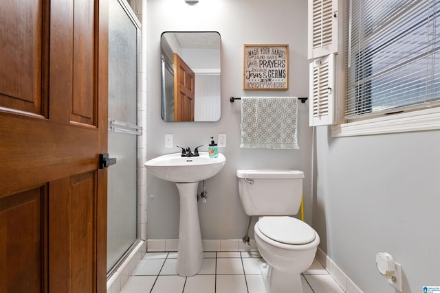 bathroom featuring tile patterned floors, a shower with shower door, and toilet