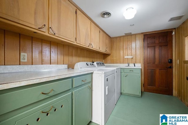 laundry room featuring cabinets, washer and clothes dryer, wooden walls, and sink