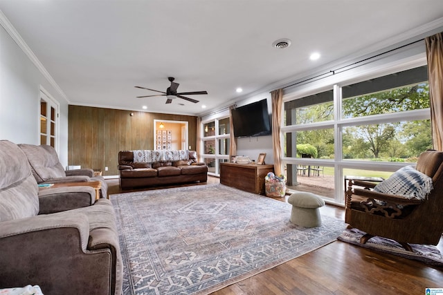 living room featuring ceiling fan, hardwood / wood-style floors, wooden walls, and ornamental molding