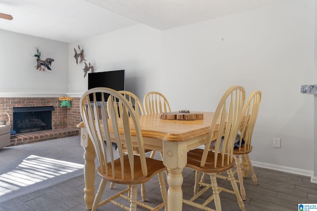 dining area featuring a textured ceiling, dark hardwood / wood-style flooring, and a fireplace