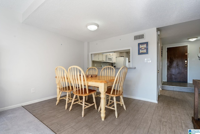 dining area featuring light hardwood / wood-style flooring and a textured ceiling