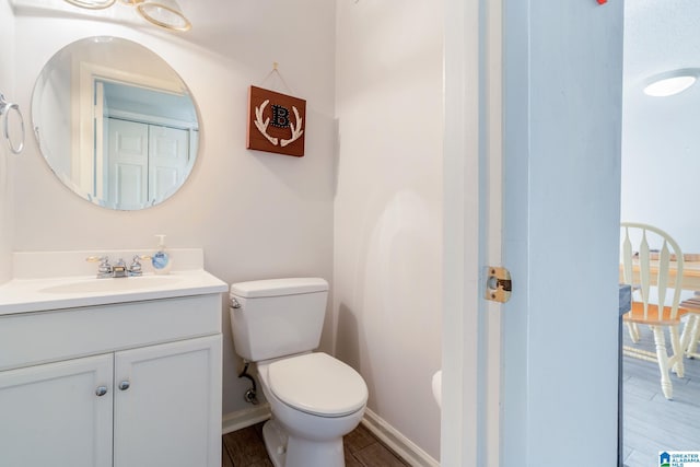 bathroom with toilet, vanity, and hardwood / wood-style flooring