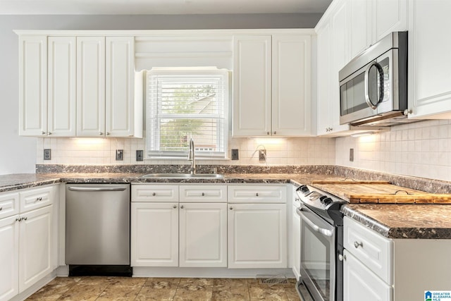 kitchen with tasteful backsplash, sink, white cabinets, and stainless steel appliances