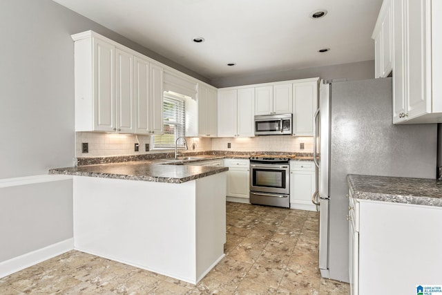 kitchen with kitchen peninsula, sink, white cabinetry, and stainless steel appliances