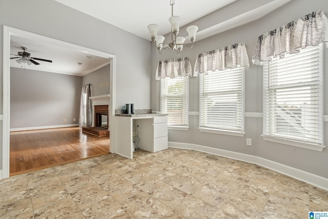 spare room with hardwood / wood-style floors, ceiling fan with notable chandelier, and a brick fireplace