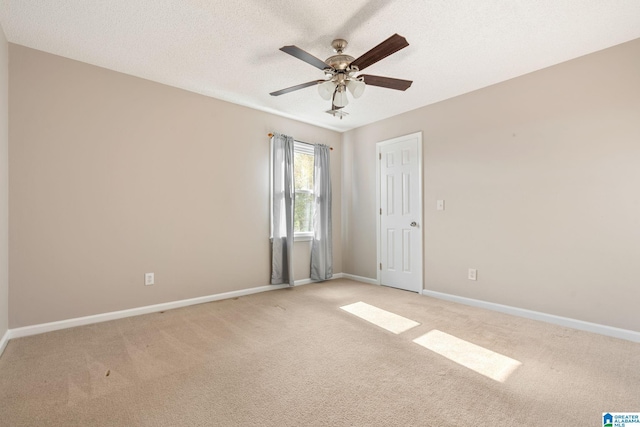 spare room with ceiling fan, light colored carpet, and a textured ceiling