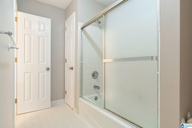 bathroom with tile patterned floors, combined bath / shower with glass door, and a textured ceiling