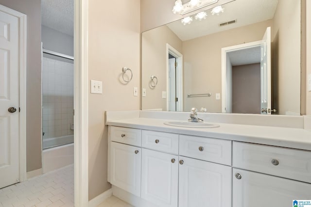 bathroom with tile patterned flooring, vanity, shower / bath combination with glass door, and a textured ceiling