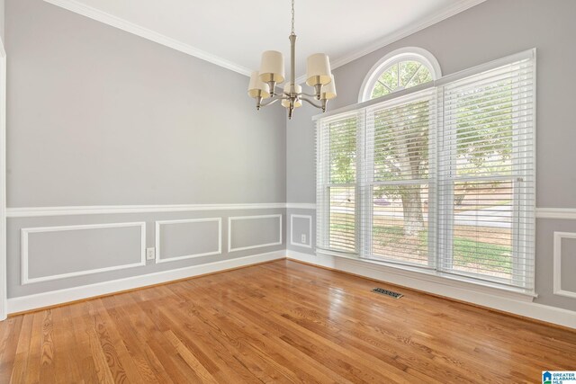 unfurnished room with hardwood / wood-style flooring, crown molding, and an inviting chandelier