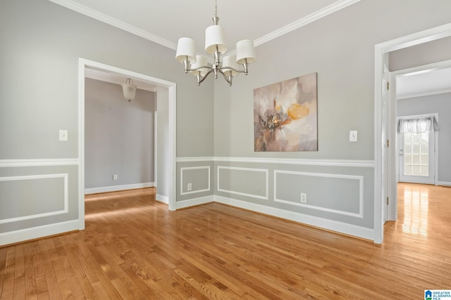 unfurnished dining area with wood-type flooring, ornamental molding, and a chandelier